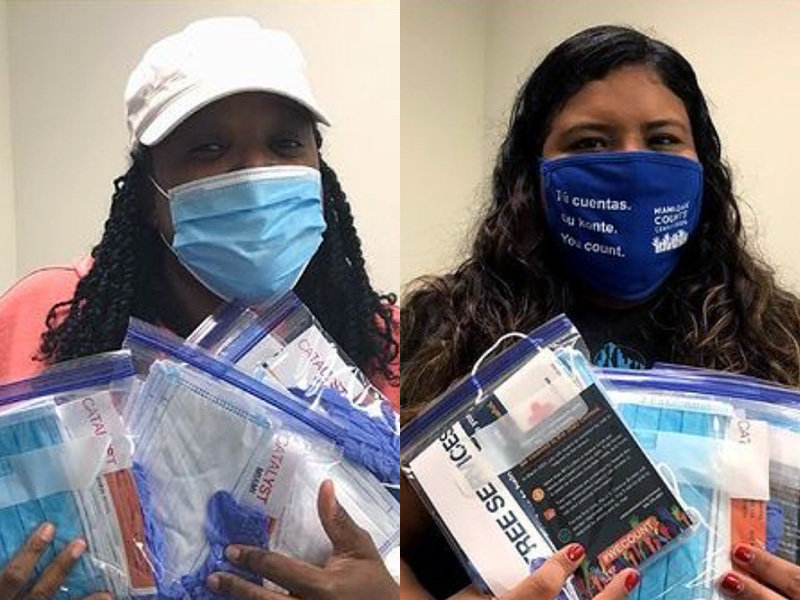 Two women holding packages of PPE to give away