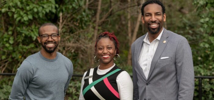 Three young black people smiling at camera
