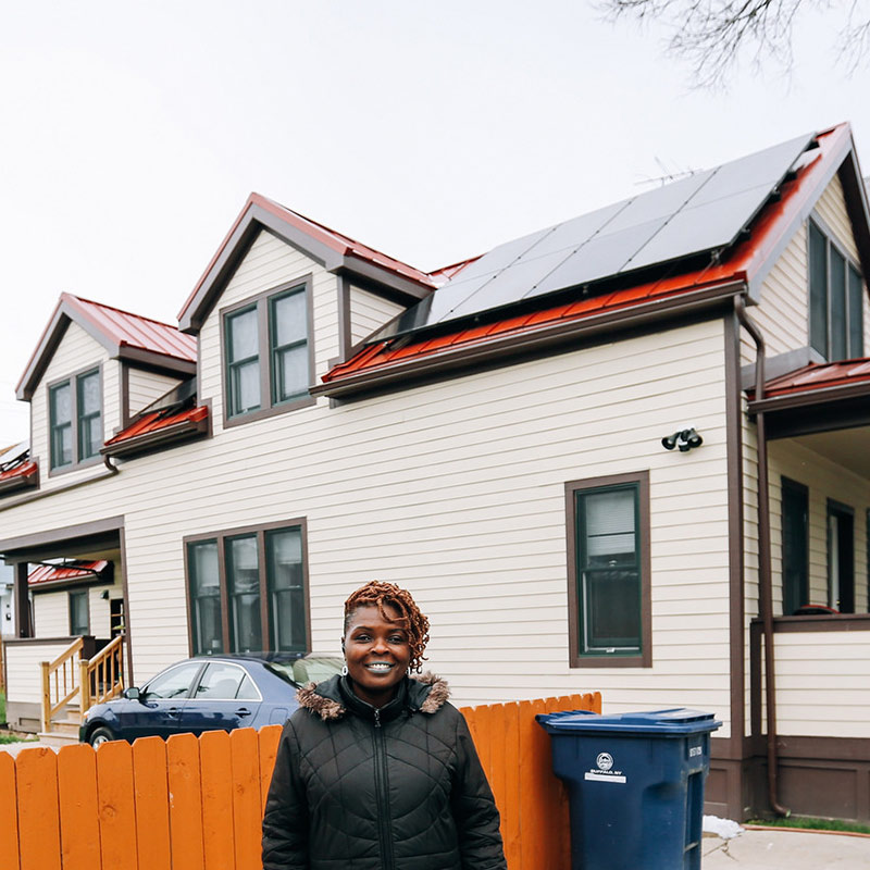 Woman stands in front of home with solar panels
