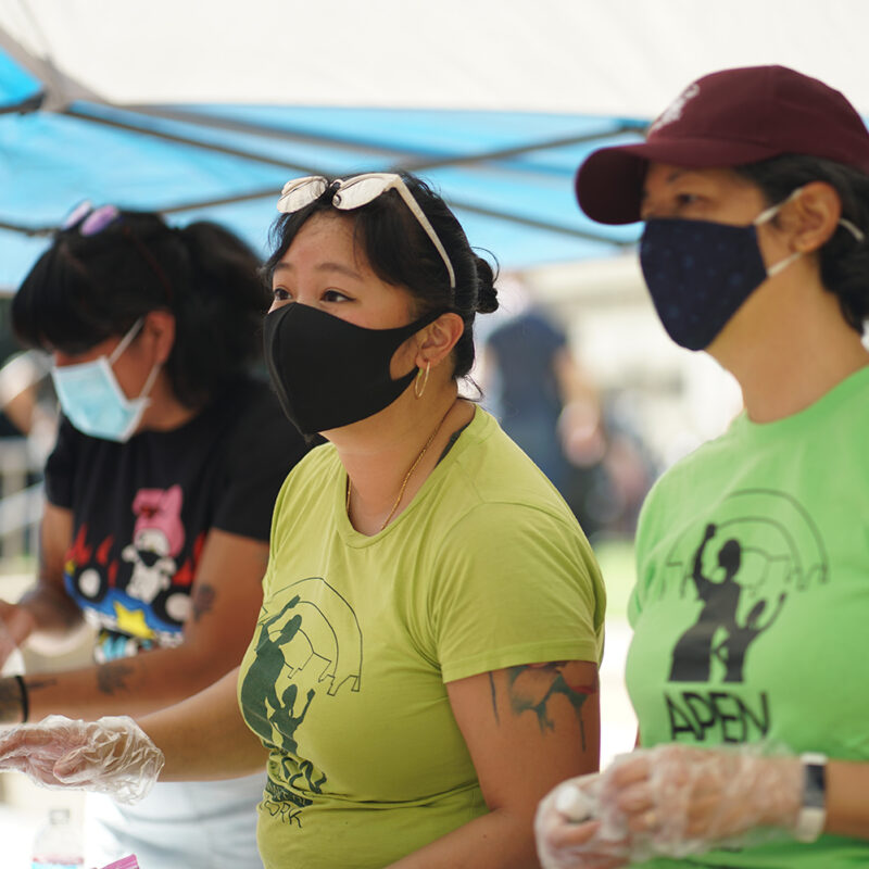 People wearing masks serving at a food line