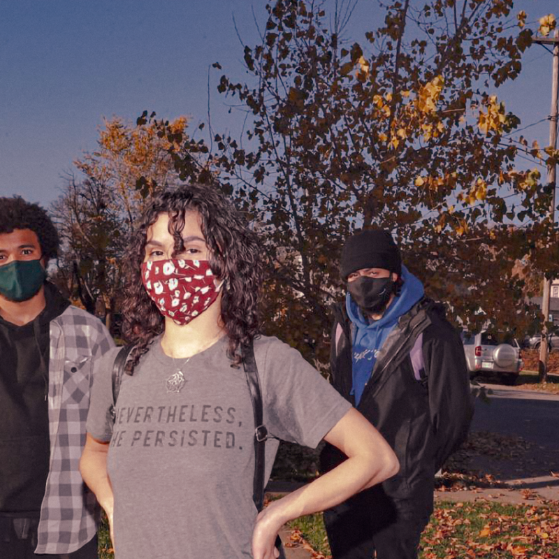 Three people in masks outdoors looking defiantly at the camera