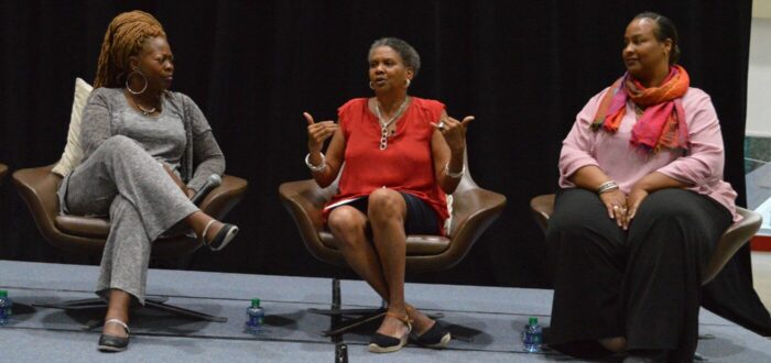 Three Black women speaking on a panel