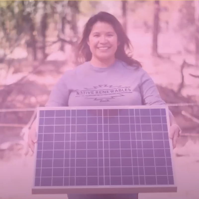 Smiling woman in Native Renewables sweatshirt holding a solar panel